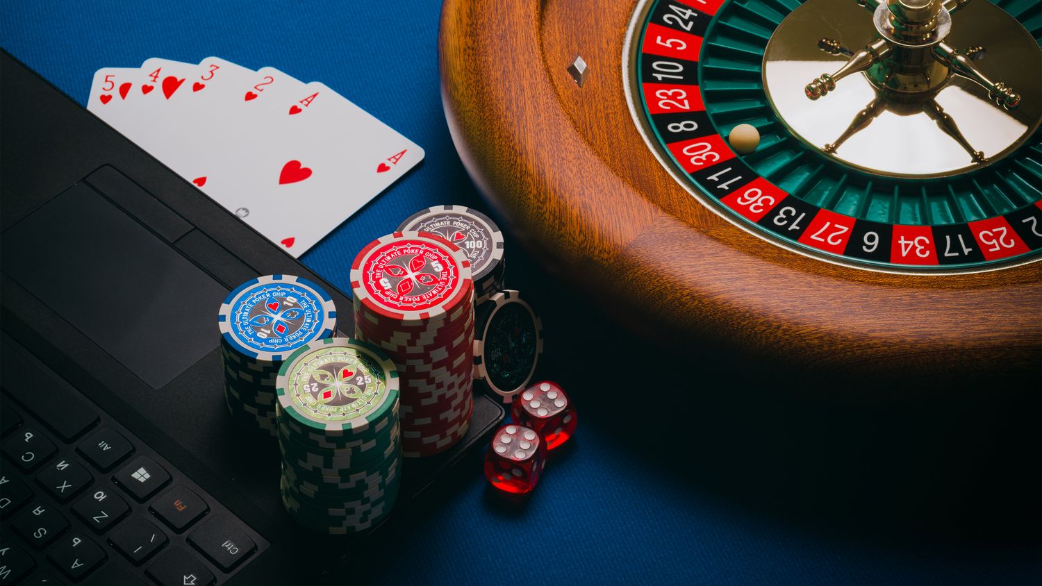Roulette wheel, casino chips and playing cards on a gaming table